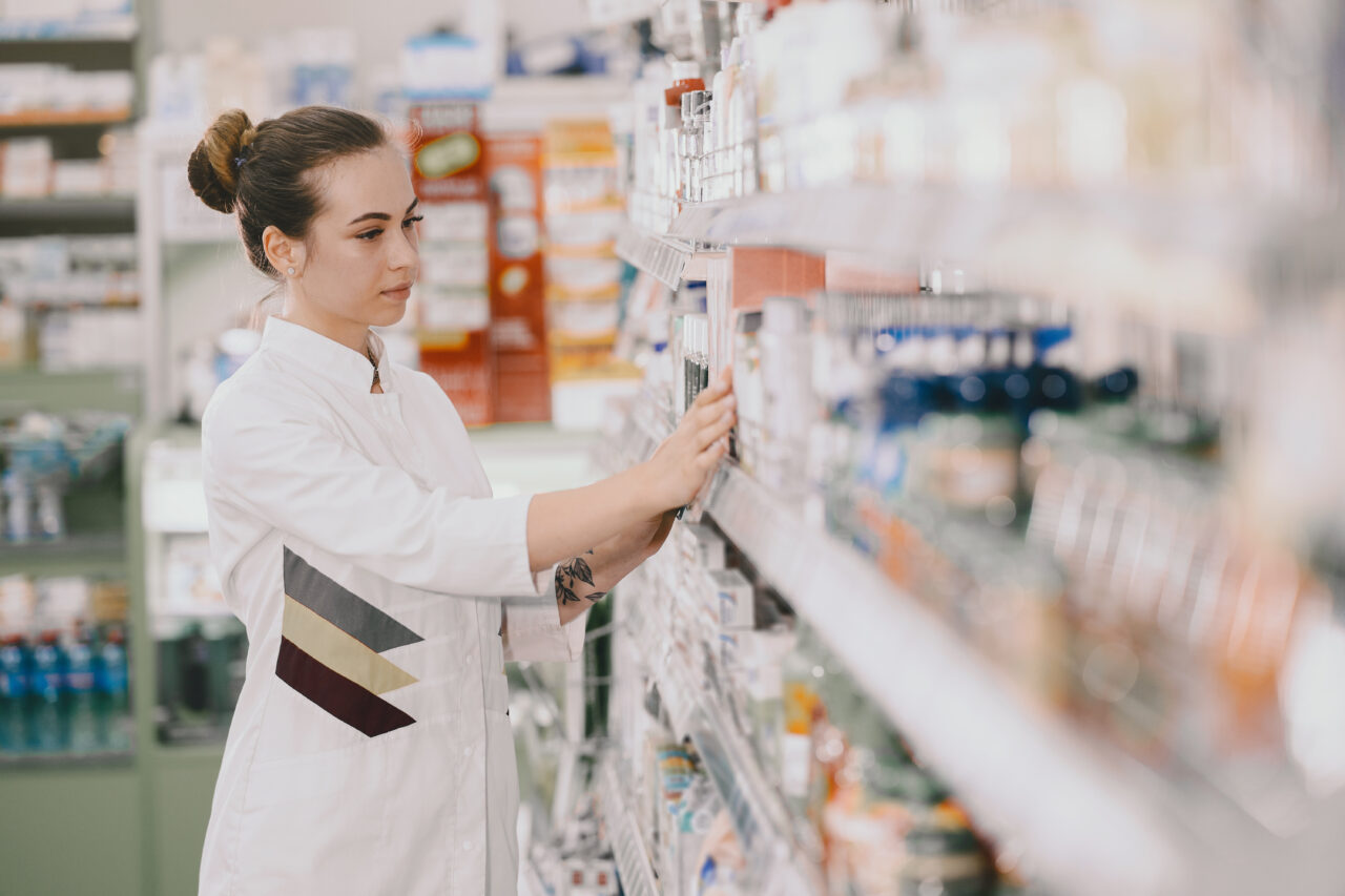 medicine pharmaceutics health care people concept female pharmacist taking medications from shelf